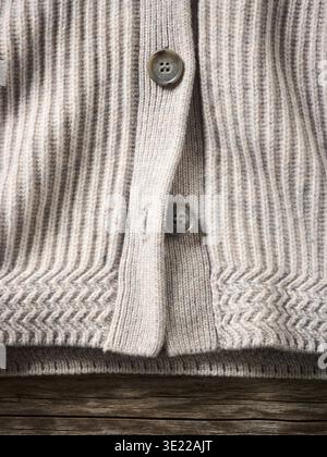 Close-up of a beige ribbed knitted cardigan with wooden buttons on wooden background Germany Stock Photo