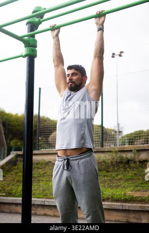 Young man doing pull-ups on bar in outdoor park workout Stock Photo