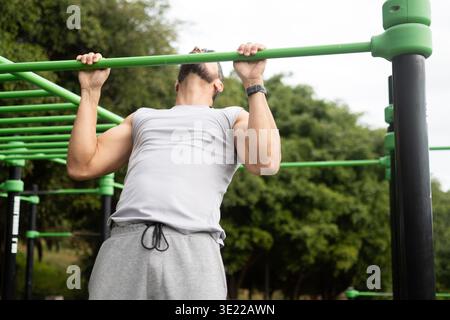 Young man doing pull-ups on bar in outdoor park workout Stock Photo