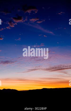Vibrant sunset with deep blue and orange hues over distant mountain silhouettes. WA, USA Stock Photo