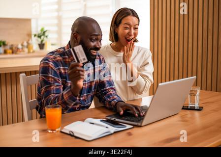 Man and woman are shopping online by using laptop at home. Stock Photo