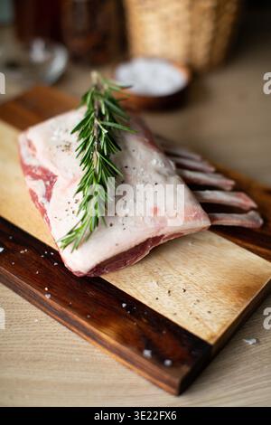 Uncooked French trimmed lamb cutlets ready for roasting, seasoned meat on a rustic kitchen surface. Stock Photo