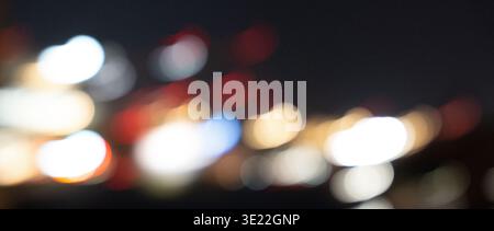 Blurred city lights at night creating a vibrant bokeh effect with various colors including red, blue, yellow, and white against a dark background Stock Photo