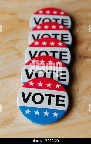 row of red, white, and blue vote badges arranged in perspective on a marble surface, political election concept with repeated badges encouraging civic Stock Photo