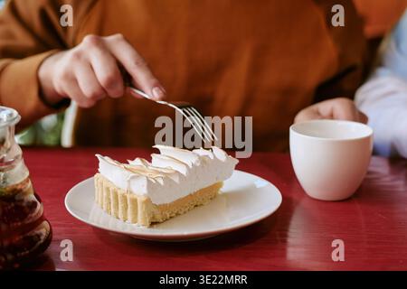 Young Adult Man Eating Cake and Drinking Coffee at Cafe Table Stock Photo