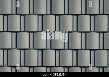 Abstract view of a modern building facade with repeating curved metal panels. Stock Photo