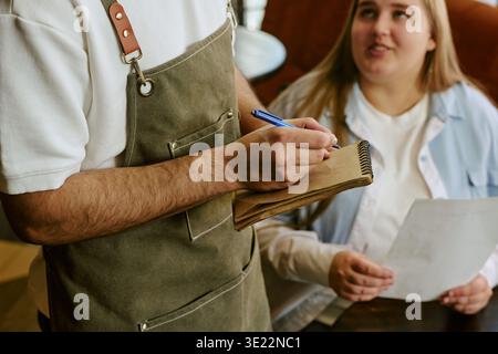 Young Woman Ordering Food from Waiter Writing on Notepad Stock Photo