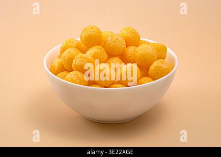 Crunchy cheese corn puff balls snack in white bowl, full depth of field Stock Photo