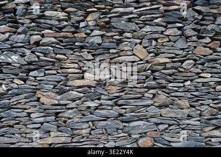 Rustic stone wall background with various shapes and sizes of rocks. Close-up of a traditional stacked stone wall, grey rock texture. Stock Photo