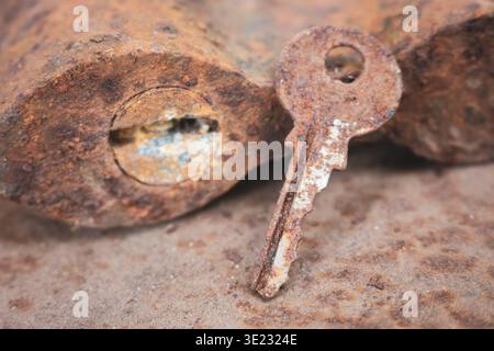 Old rusty key and lock. Vintage door padlock with key. Antique key on weathered background. Security and safety concept. Aged iron key and padlock. Stock Photo