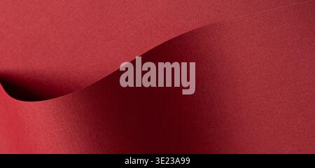 Woven fabric texture in deep burgundy and wine tones fills the background. Soft matte textile surface shows layered folds with gentle wave and depth. Stock Photo