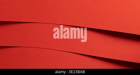 Horizontal red paper bands create a bold layered background with graphic rhythm. Smooth matte strips overlap with subtle depth and shadow forming a cl Stock Photo