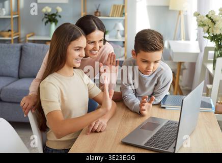 Mother And Kids Participating In Online Video Call Using Laptop At Home Stock Photo