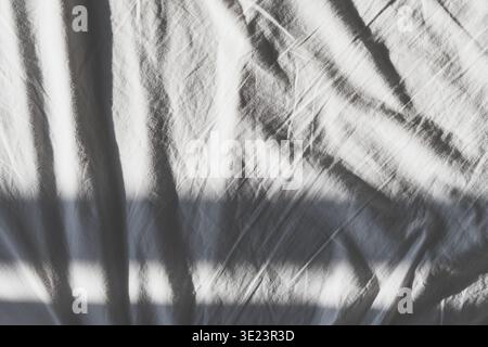 White fabric shows textured wrinkles and folds with morning light creating abstract shadows Stock Photo
