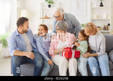 Three generations family portrait, congratulating hugging beloved senior grandma, close embracing Stock Photo