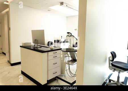 High-angle view of a modern minimalist office workstation. A closed black laptop, computer mouse, and white router sit on a clean, black ergonomic des Stock Photo