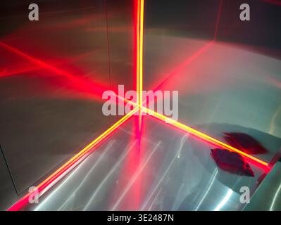 Futuristic abstract background featuring bright red neon light lines reflecting perfectly in the corner of a polished stainless steel or metallic surf Stock Photo
