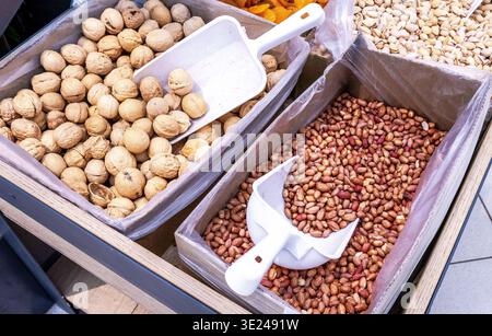 Unpeeled walnuts and peanut are sold in a grocery store, close up Stock Photo