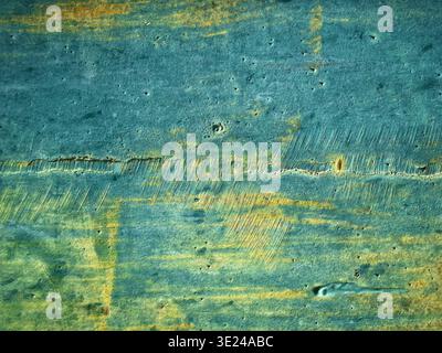 Close up view of a distressed wooden surface with textured blue and yellow paint layers showing wear and scratches Stock Photo