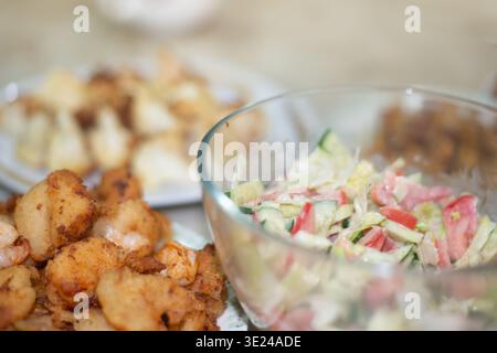 Tomato and cucumber salad in sour cream and fried in batter curves are on the table authentic homemade food photo. High quality photo Stock Photo