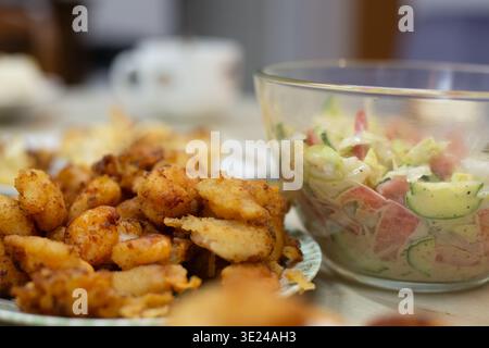Tomato and cucumber salad in sour cream and fried in batter curves are on the table authentic homemade food photo. High quality photo Stock Photo