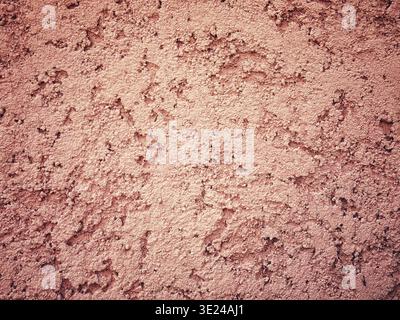 Close up view of a rough textured pink cement or concrete wall surface showing a rustic and weathered architectural pattern Stock Photo