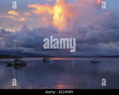 Boats on still water at sunset, sky glowing in blue and orange, dramatic cloud formations, Port Douglas, Australia Stock Photo