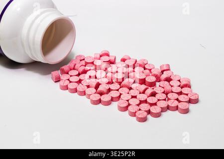 The concept of medicines and healthcare. A large number of round pink zinc gluconate tablets and white bottle on a white background, zinc gluconate is Stock Photo