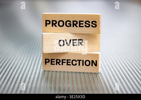Progress beyond perfection. Sentence written on wooden tablets. Business concept. Motivating, supporting development. Close up. copy space Stock Photo