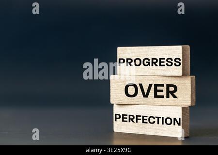 Progress beyond perfection. Sentence written on wooden tablets. Business concept. Motivating, supporting development. Close up. copy space Stock Photo