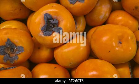 Fresh ripe persimmons with vibrant orange color, healthy organic fruit background Stock Photo