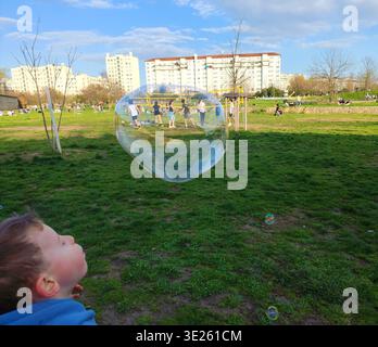 Lyon,France-March 8,2026:Boy in casual clothes blowing soap bubbles in public park Blandan Stock Photo
