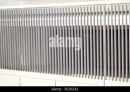 White metal fence with vertical bars integrated into a modern architectural building facade Stock Photo