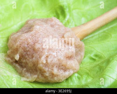 Salty caviar of zander fish in wooden spoon on green leaf close up Stock Photo