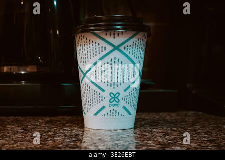 Dixie disposable paper coffee cup with black lid and teal pattern on granite kitchen countertop Stock Photo