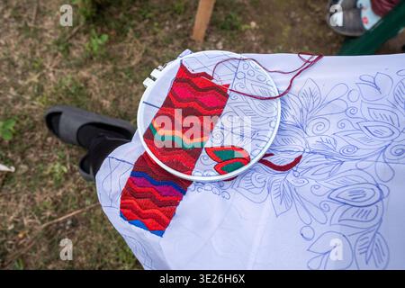 Aguacatan, Guatemala - Bright hand embroidery in a hoop shows colorful wavy and floral stitches on white fabric, a detailed textile craft project phot Stock Photo