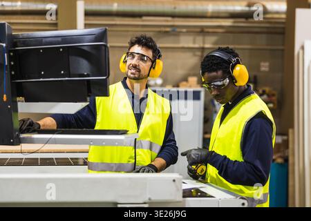 Millworkers operating cnc machine in carpentry workshop Stock Photo