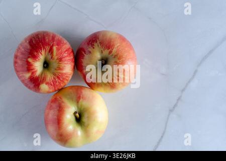 Top view of three fresh, juicy red apples arranged on a clean textured background Stock Photo