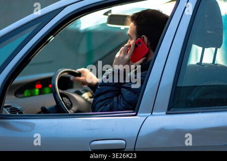 Driver distracted using mobile phone while operating vehicle Stock Photo