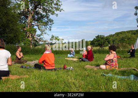 Group practicing yoga and meditation in natural outdoor setting Stock Photo