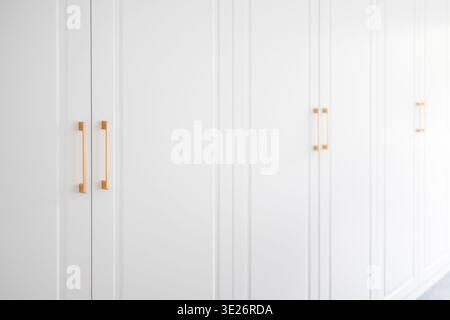 luxury modern white wardrobe with golden handles side perspective, showcasing sleek minimalist coastal interior design, elegant furniture and contempo Stock Photo