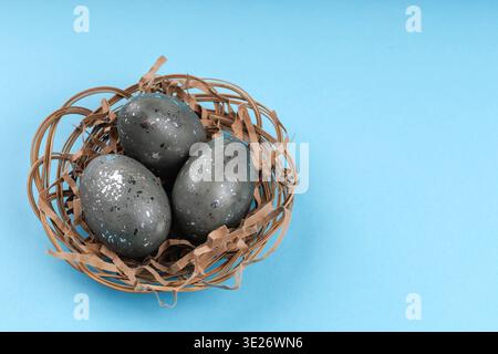 Decorative Easter eggs with silver texture in nest on blue background Stock Photo