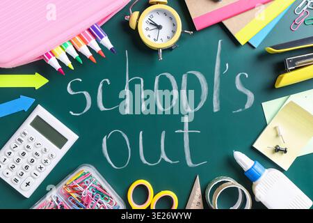 Phrase School's Out and school supplies on chalkboard, flat lay Stock Photo