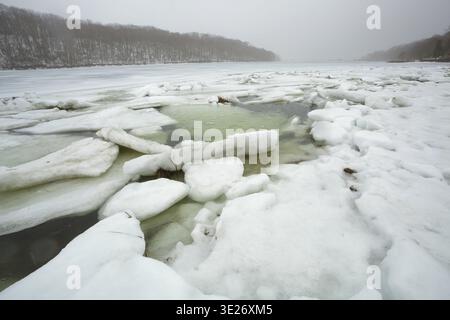 Wide-angle ice floes in deep winter. Atmospheric coastal winter landscape with frozen harbor and a misty shoreline. Stock Photo