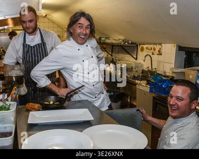 Paul Clerehugh chef at the Crooken Billet restaurant in oxfordshire and other chefs cooking and smiling in  kitchen Stock Photo