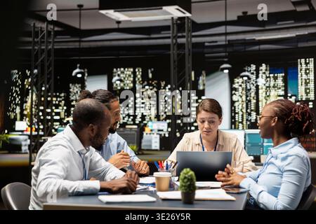 Office employees doing business meeting to plan project, using laptop and paperwork to design marketing strategy. Businesspeople doing research analysis for startup organization using notebook Stock Photo
