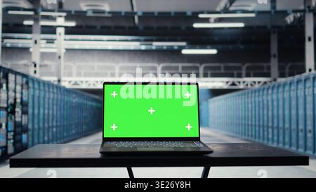 Close up of green screen laptop in data center used for inspecting equipment rigs, maintaining system stability. Mockup notebook used to oversee server hub and configure gear rackmounts Stock Photo