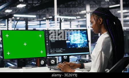 Data center engineers managing AI systems for uptime and efficiency using chroma key PC. Teamworking IT specialists using artificial intelligence on green screen computer in server hub, camera A Stock Photo