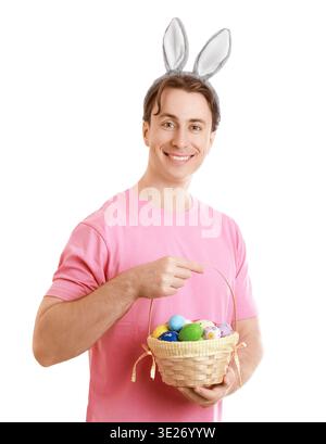 Smiling young man wearing bunny ears holding a basket full of colorful Easter eggs. Isolated on a white background. Perfect for Easter holiday and fam Stock Photo