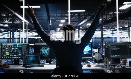 Delighted developer celebrating in data center after successfully coding with generative AI. Overjoyed employee doing high five with colleague after leveraging AI large language model, camera A Stock Photo